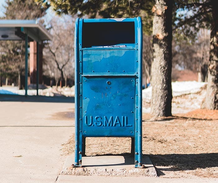 a blue mailbox on the sidewalk